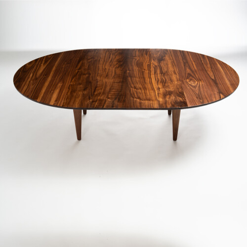 Convertible walnut table lowered to coffee height, oval book-matched top