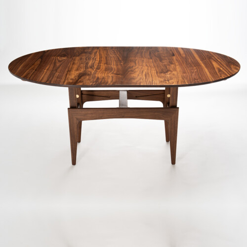 Convertible walnut table raised to dining height, book-matched top and brass detail